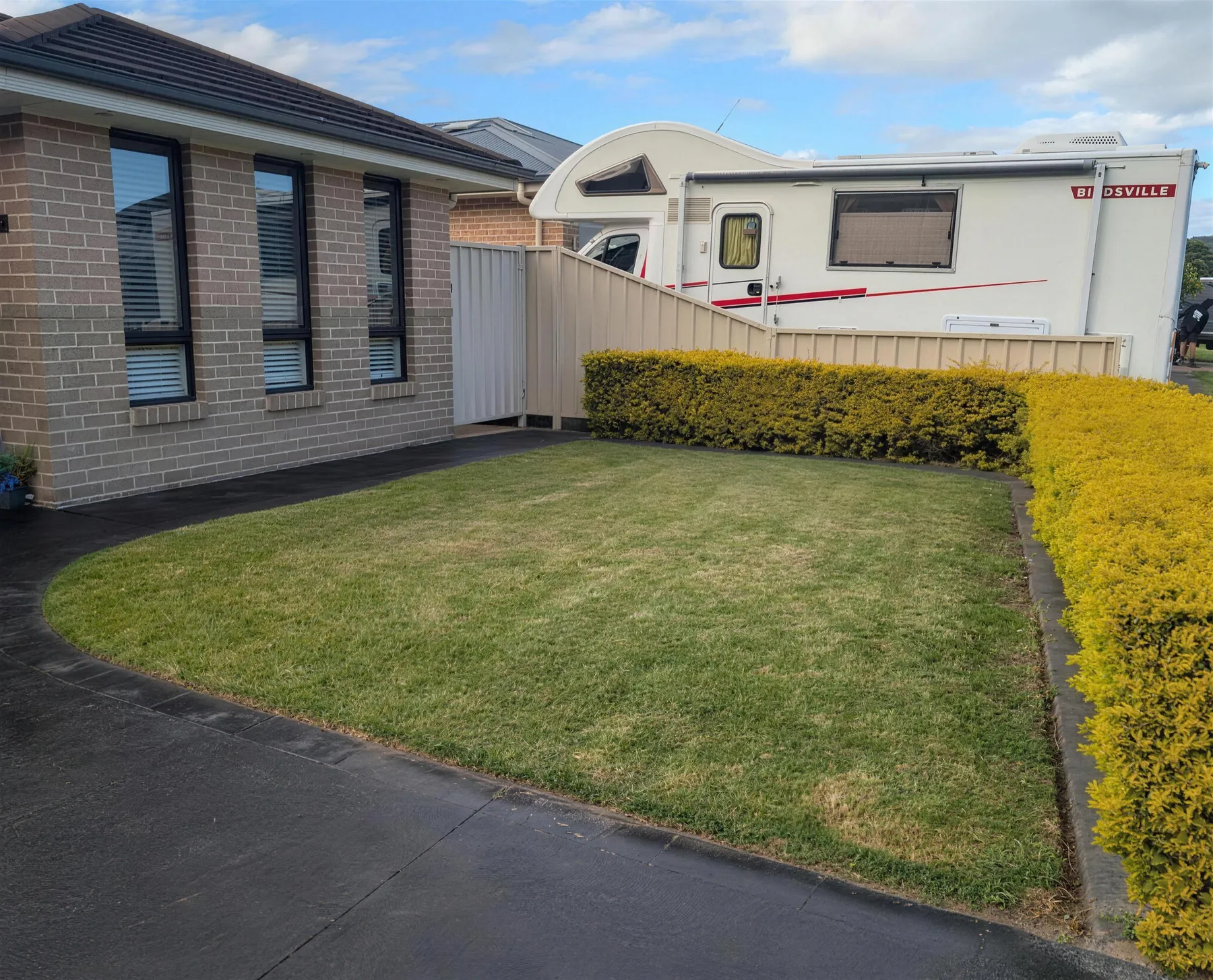 A neat green front lawn with crisp edges beside a brick house