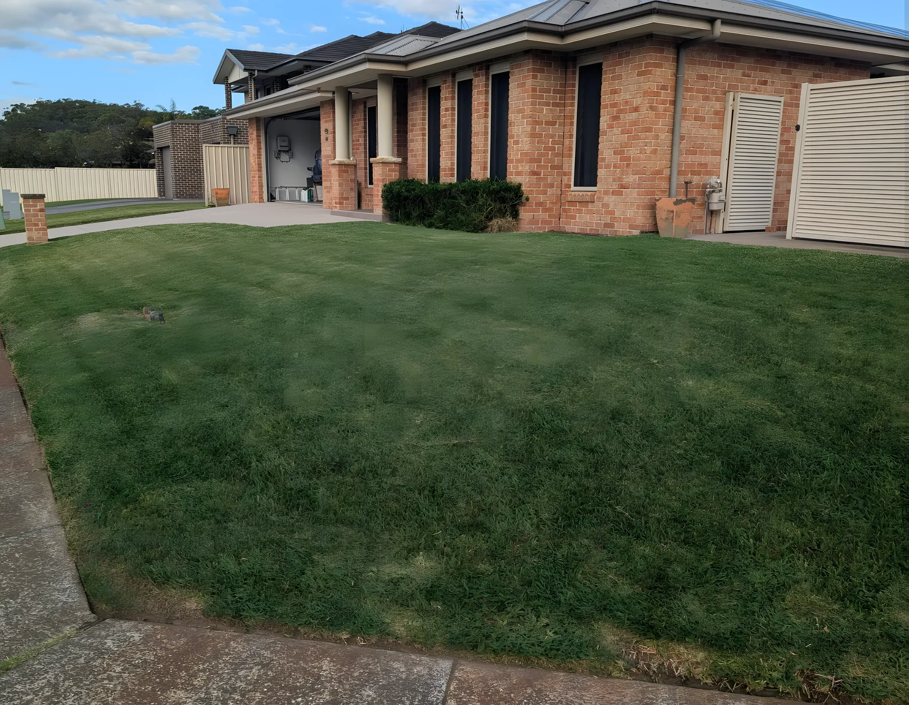 A thick, freshly mown front lawn wrapping a brick home